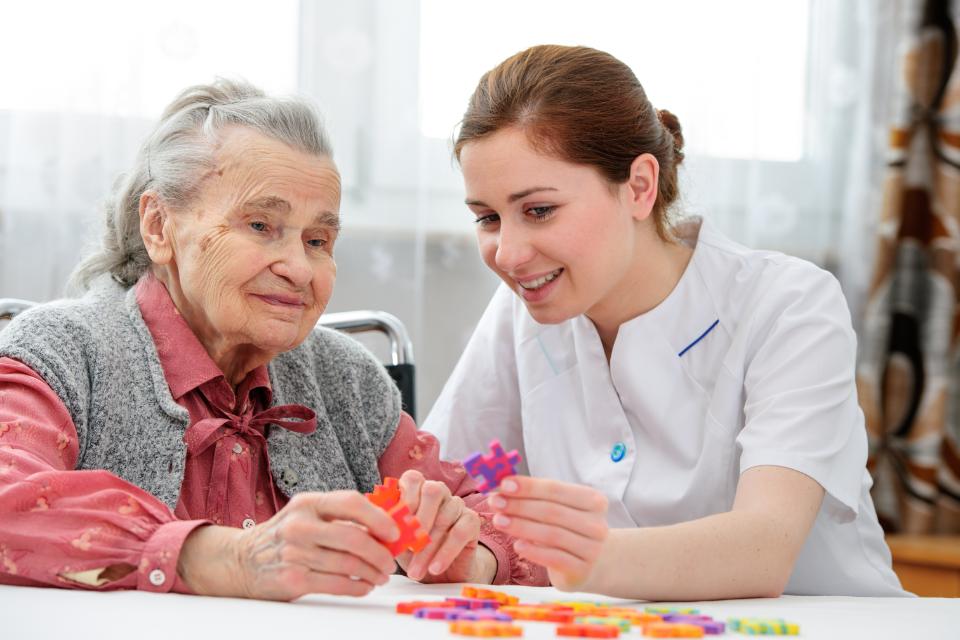 Caregiver playing puzzle with elderly lady