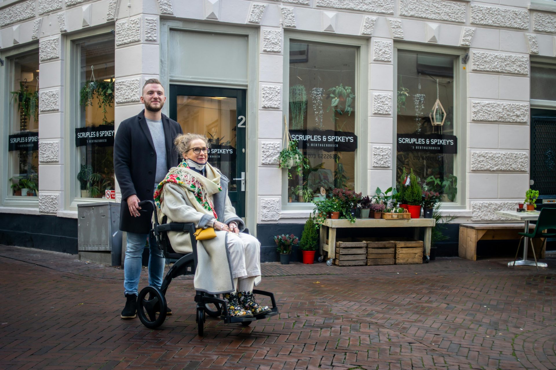 Elderly woman in wheelchair with companion outdoors in 's-Hertogenbosch.